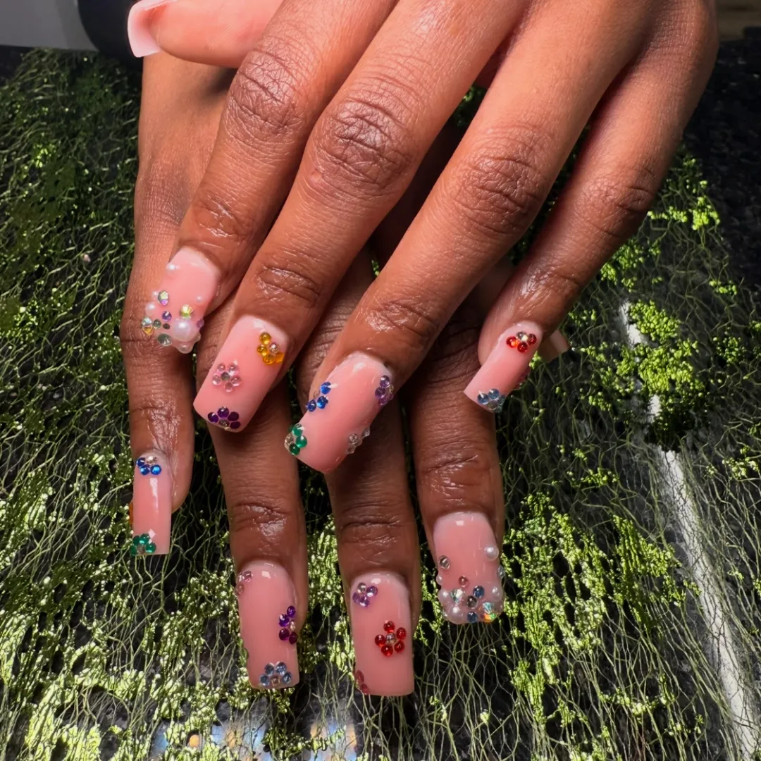 Nude nails with rainbow rhinestone flower accents